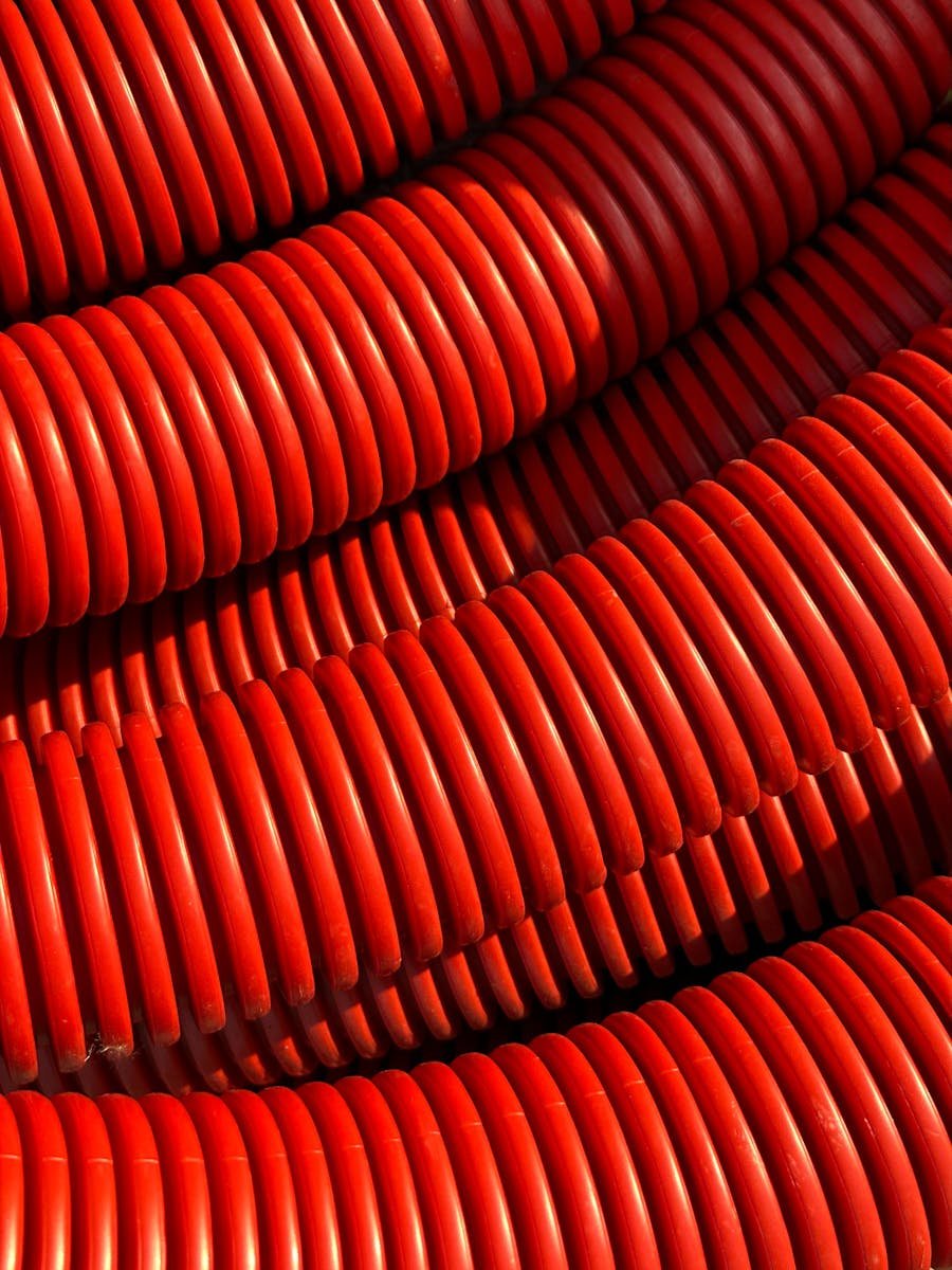 A close-up view of vibrant red industrial pipes arranged in a pattern, captured in sunlight.